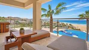 Ein Balkon mit Pool, Liegestühlen und Blick auf Strand und Meer.