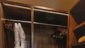 A walk-in closet with a wooden wardrobe and a mirrored closet door. - Beachfront Luxury 3 BR Condo in Diamante Dunes (Cabo San Lucas)