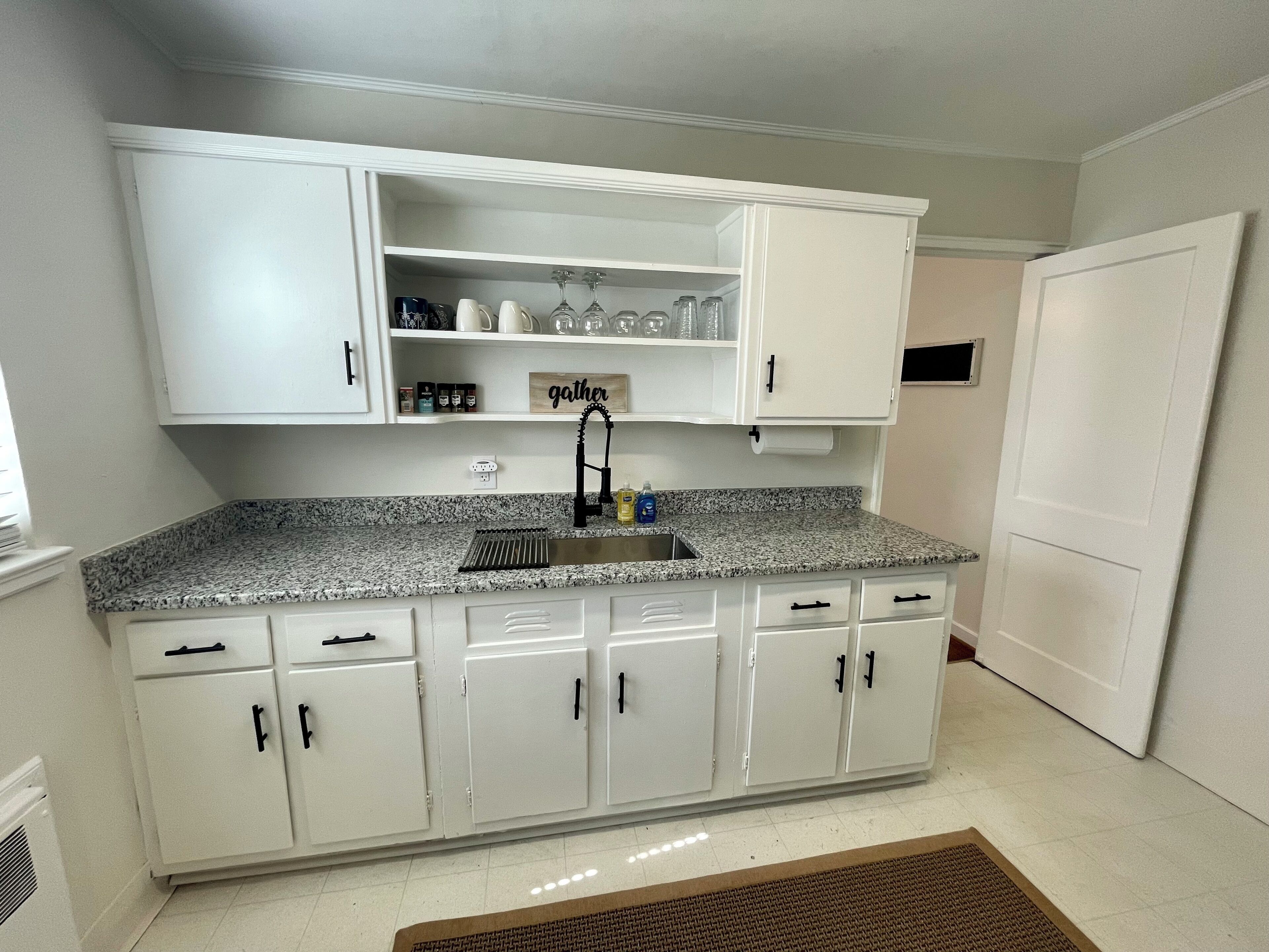 A kitchen with white cabinets, a granite countertop, and a built-in sink.
