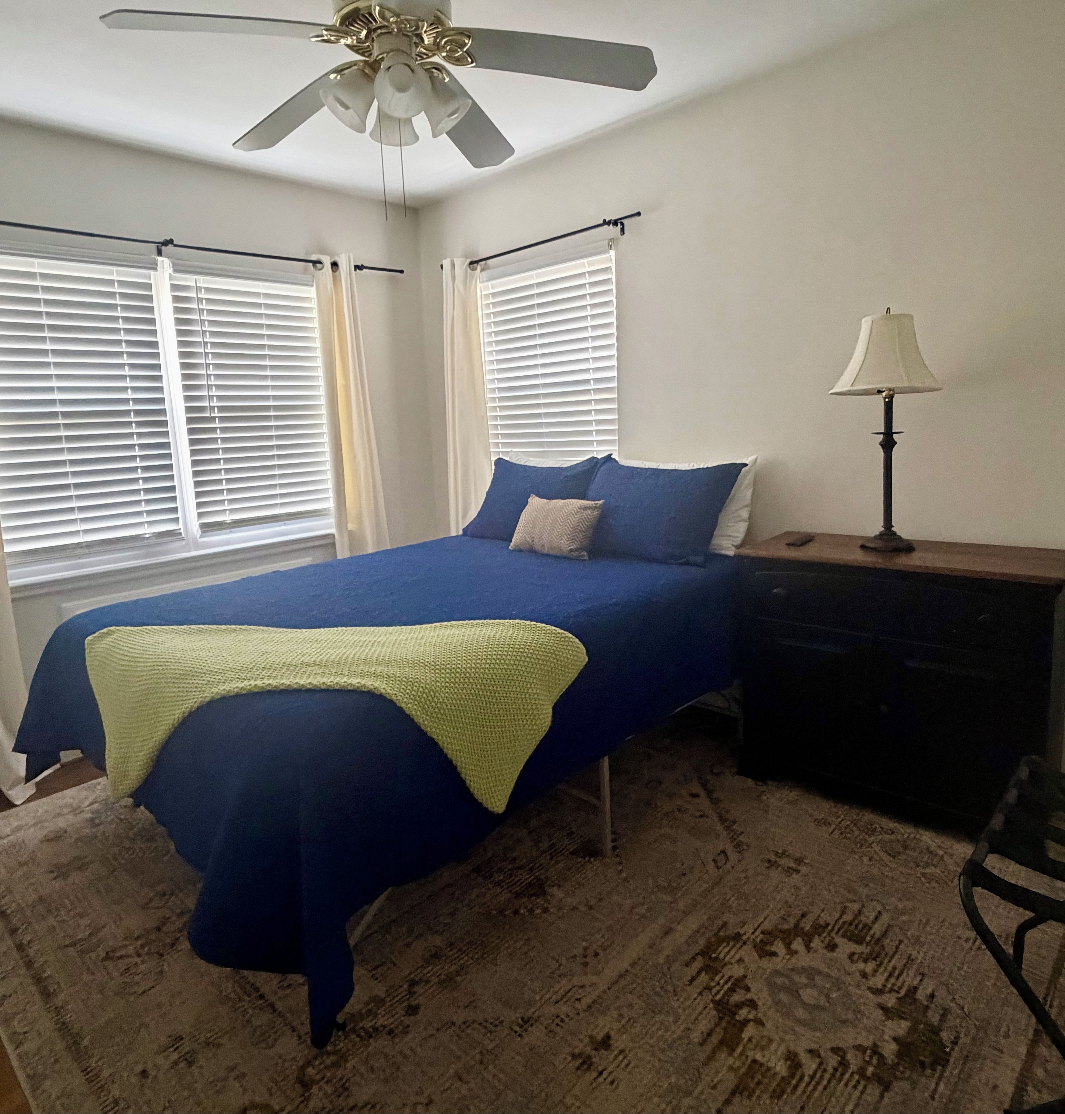 A bedroom with a bed, a nightstand, a lamp, and a ceiling fan.