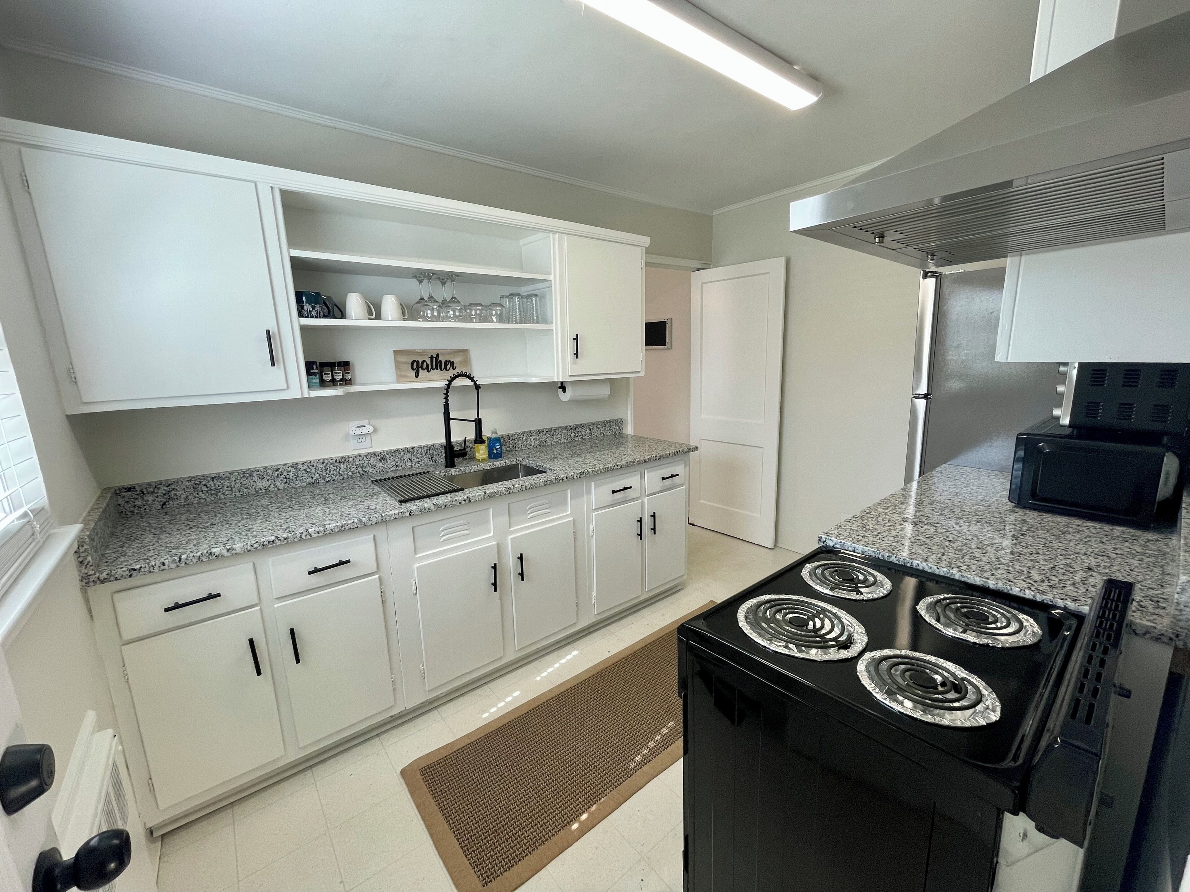 A kitchen with white cabinets, a black stove, and a microwave.