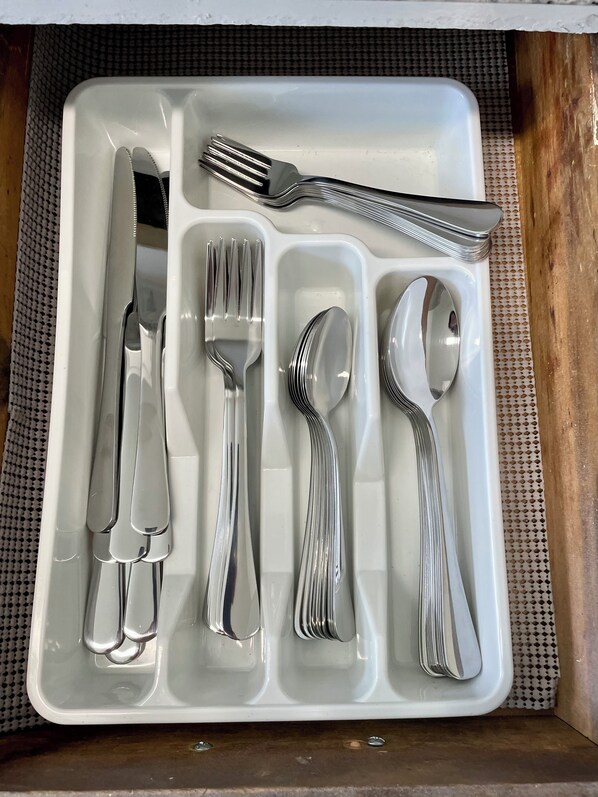 A drawer with neatly arranged silverware including forks, knives, spoons, and a butter knife.
