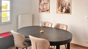 Un coin repas comprenant une table ronde, six chaises et deux œuvres d’art encadrées accrochées au mur.