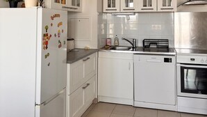 Une cuisine moderne avec des meubles blancs, une hotte en acier inoxydable et un lave-vaisselle.