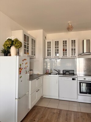 A modern kitchen with white cabinetry, a stainless steel range hood, and a dishwasher. - 3-room apartment next to Disney and Vallée Village with a 7.4 kWh charging station (Serris)