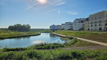 Vista al río con cielo despejado, una masa de agua tranquila y una hilera de edificios residenciales de varios pisos.