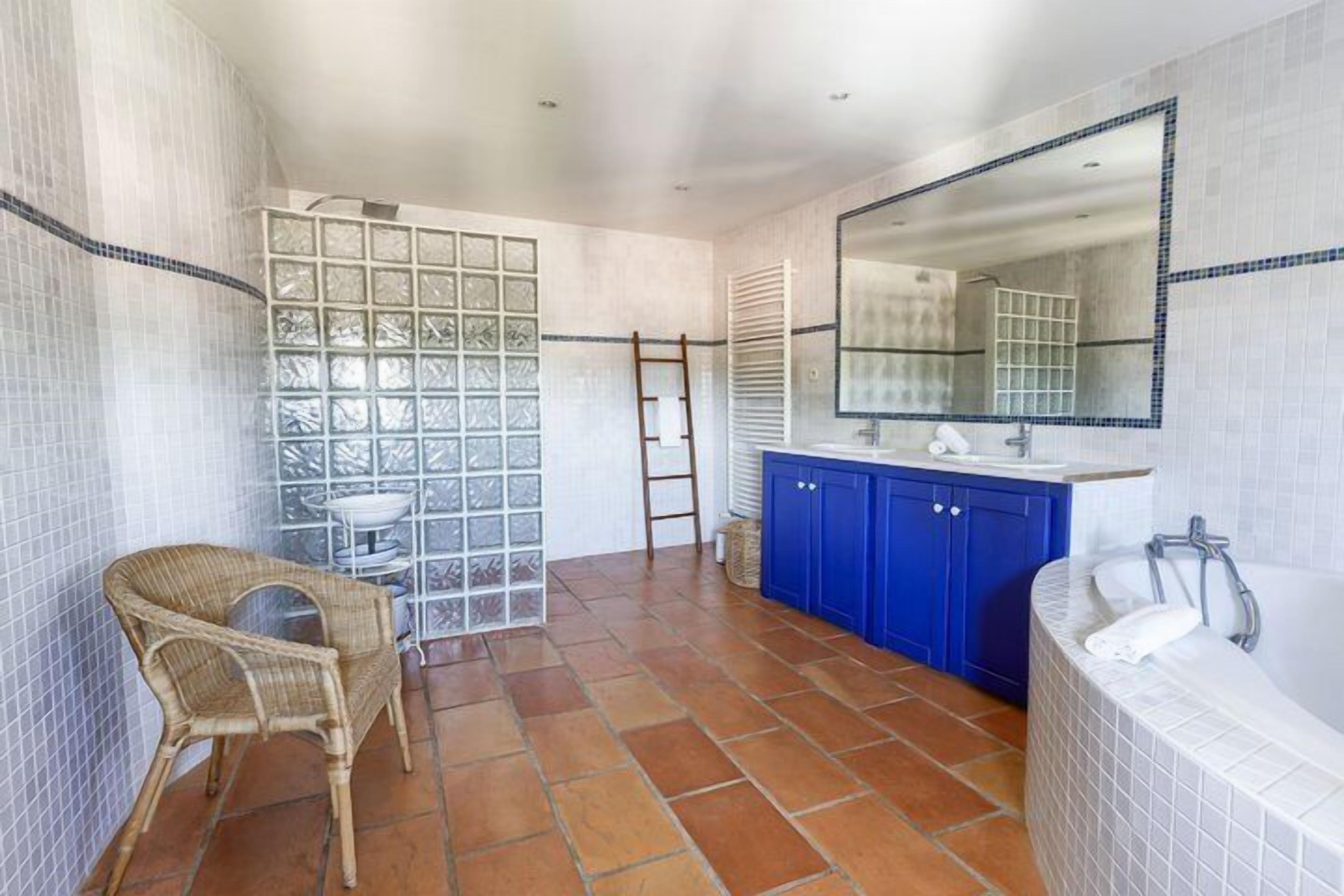 Een badkamer met een douche, een bad, een wastafel en een stoel.