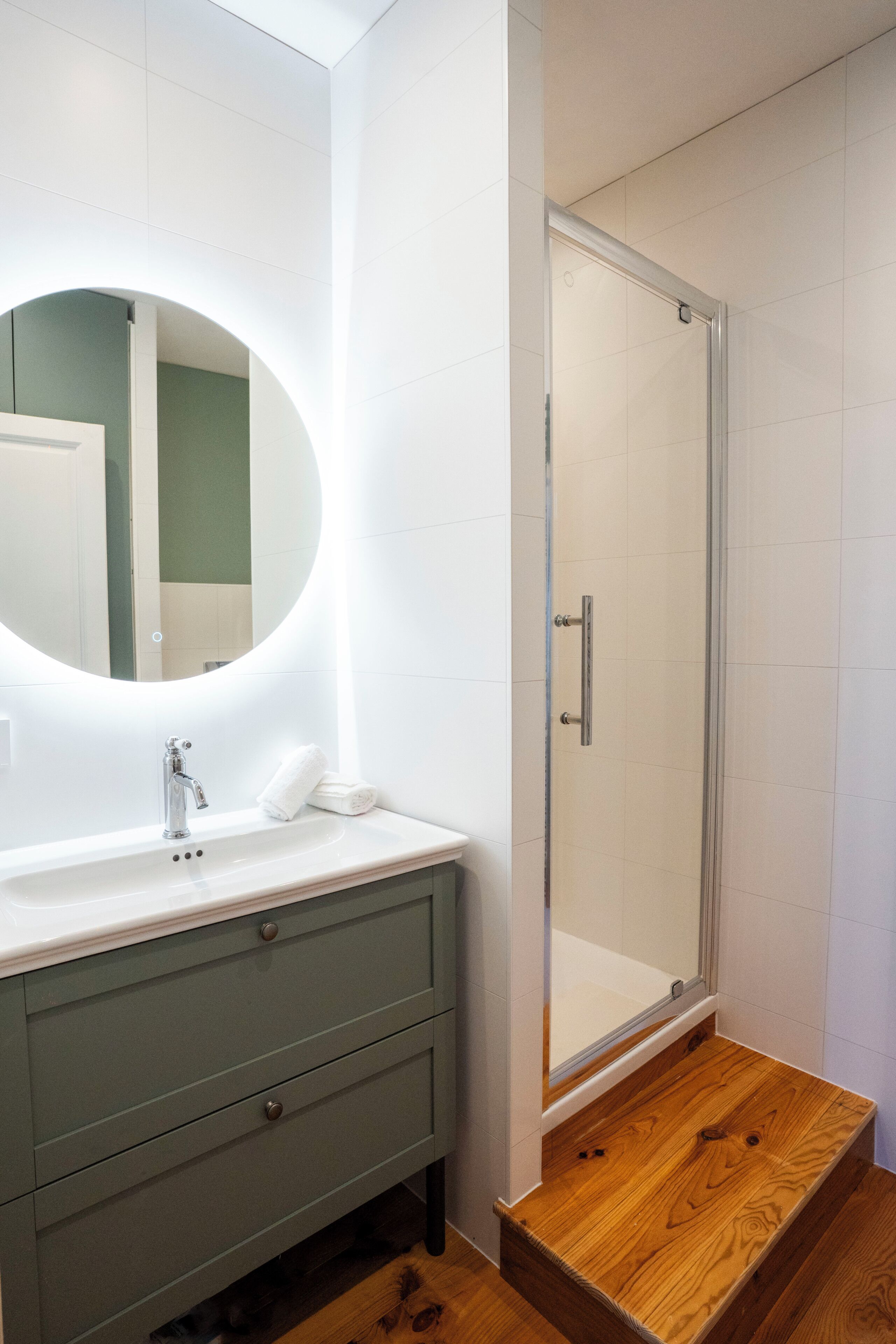 Une salle de bain avec un lavabo blanc, un miroir et une cabine de douche en verre.
