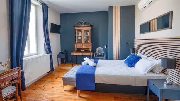 Habitación de hotel con cama, un armario de madera, escritorio, silla y ventana con cortinas.