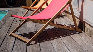 Dos sillones de madera con cojines rojos, ubicados en una terraza de madera junto a un mural colorido.