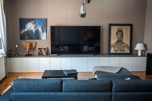A modern living room with a large flat-screen TV, a sofa, and artwork on the wall.