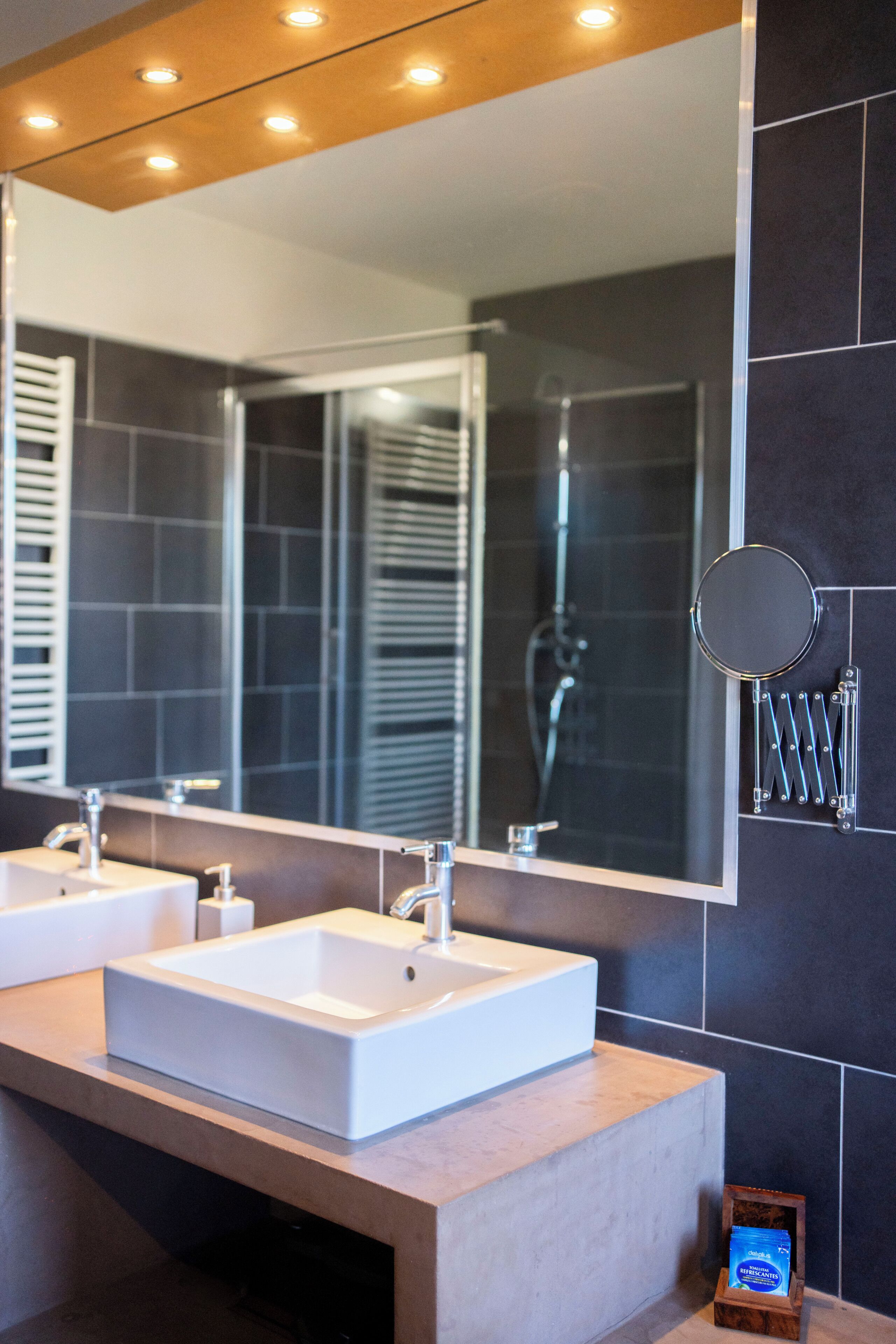 A bathroom with two sinks, a large mirror, and a shower area.
