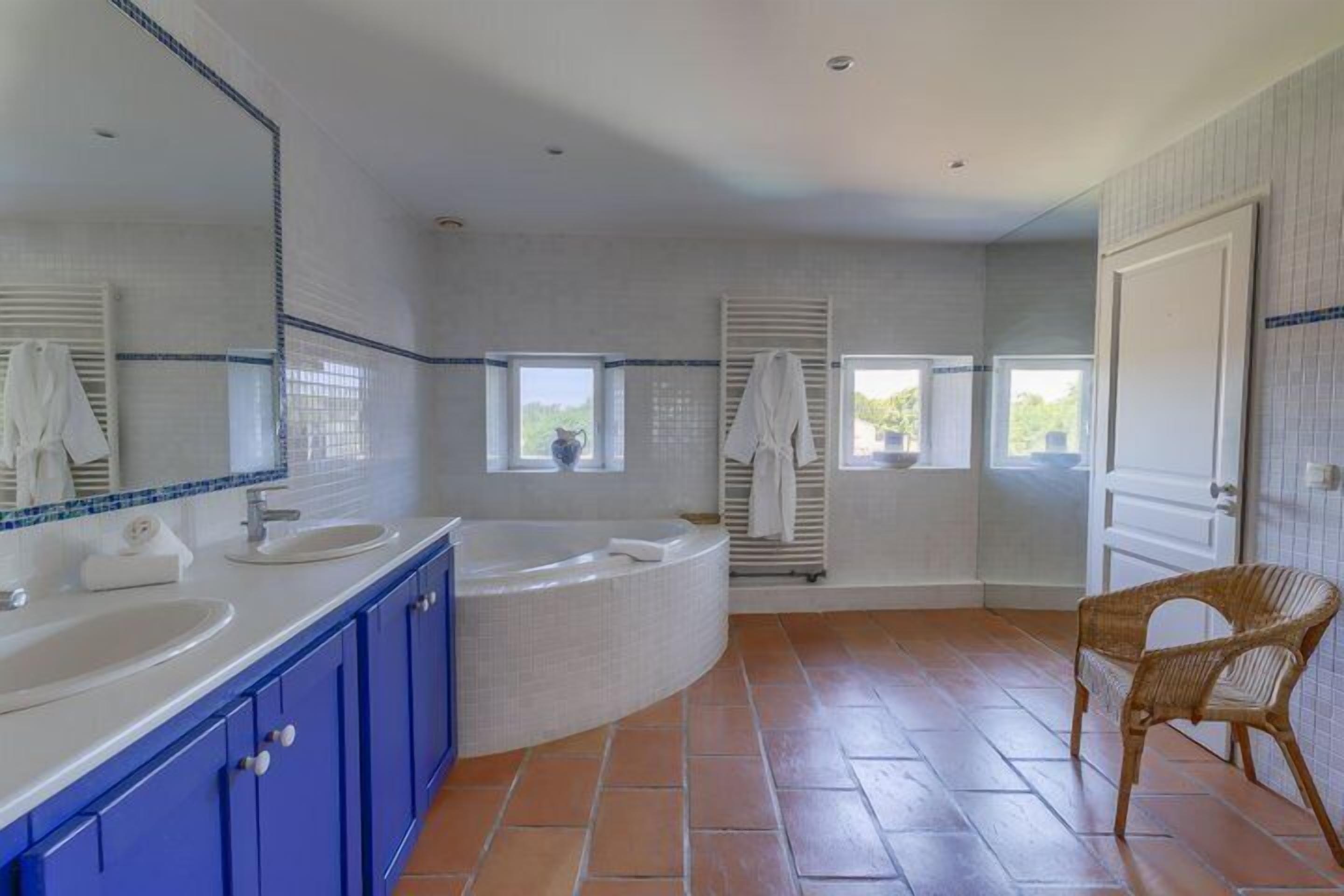 A bathroom with two sinks, a bathtub, and a window.