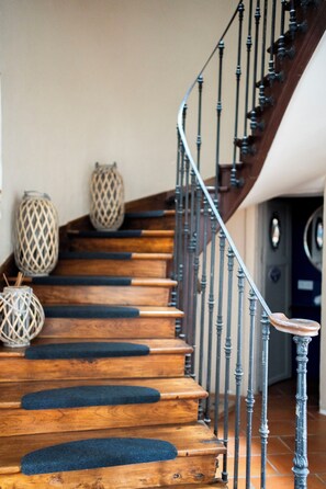 A wooden staircase with a metal railing, leading to a dark room. - Maison Bacchus 31 (Buzet-sur-Tarn)