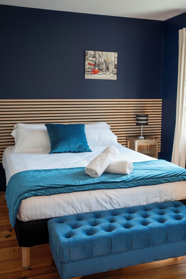 A bed with a blue headboard, white bedding, and a blue pillow.