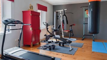 Ein Heimfitnessraum mit Laufband, Hantelbank, Kurzhanteln und einem Schlagring.