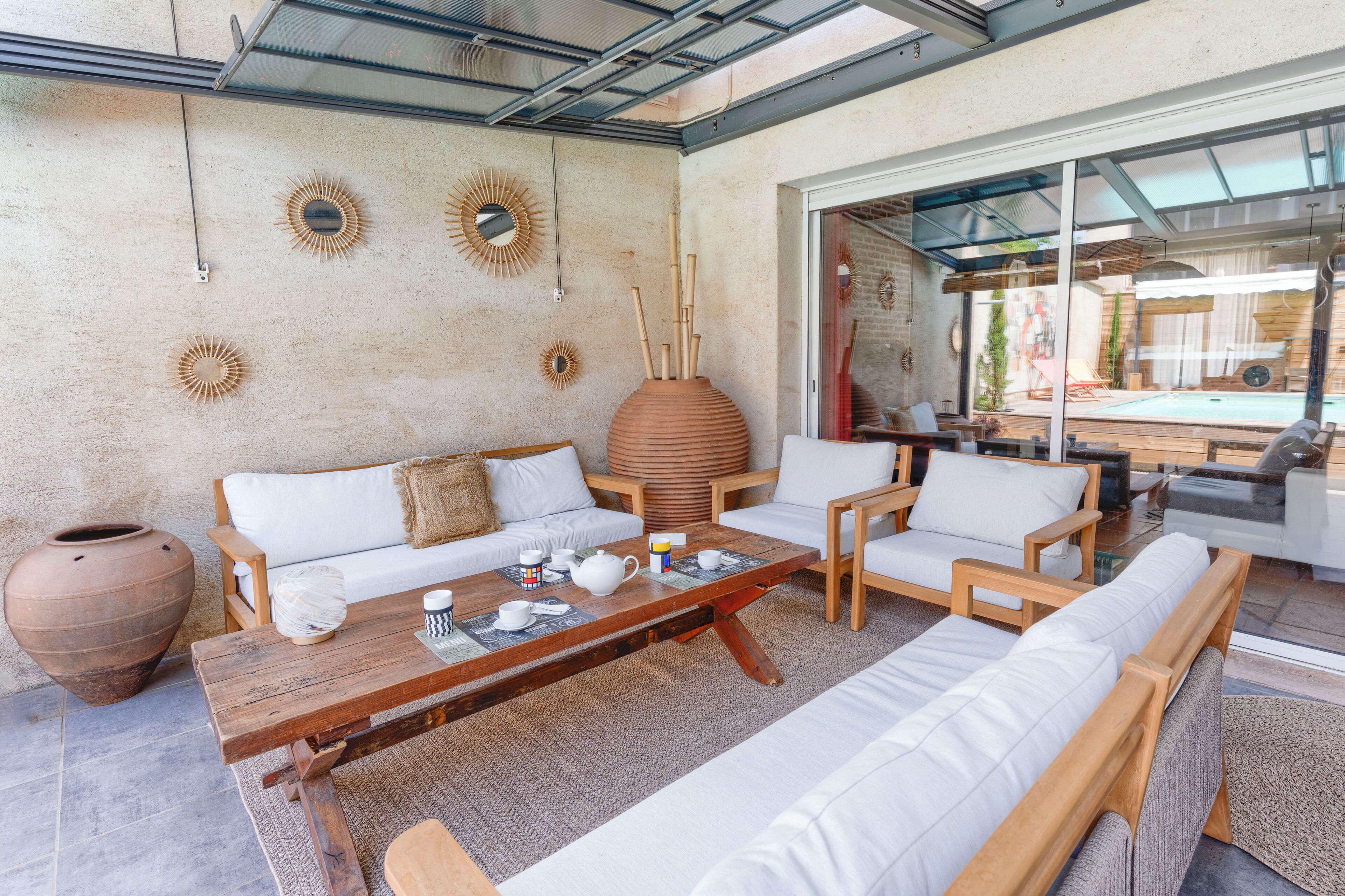 A modern outdoor living space with a sofa, chairs, a coffee table, and decorative sunburst wall art.