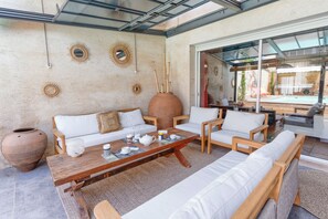 Een moderne buitenruimte met een bank, stoelen, een bijzettafeltje en decoratieve zonstraal-wandkunst.