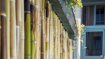 A bamboo fence with a wooden deck and a blue door in the background.