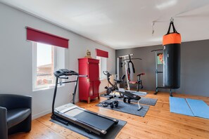 A home gym with a treadmill, stationary bike, elliptical, and a punching bag.
