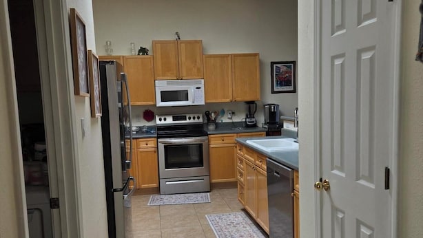 A kitchen with wooden cabinets, a microwave, an oven, a sink, and a door with a brass handle. - Beautiful 3-bed house in Los Ranchos.  Balloon fiesta park is just minutes away. (Albuquerque)