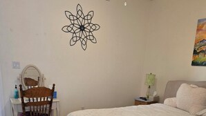 A bedroom with a bed, a chair, a desk, a wall decoration, and a painting. - Beautiful 3-bed house in Los Ranchos.  Balloon fiesta park is just minutes away. (Albuquerque)