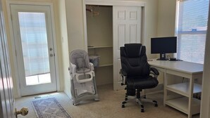 A room with a ceiling fan, a desk with a computer, a chair, a stroller, and a door with a window. - Beautiful 3-bed house in Los Ranchos.  Balloon fiesta park is just minutes away. (Albuquerque)