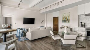 Ein modernes Wohnzimmer mit einer Couch, einem Glastisch und einem Essbereich mit Stühlen.