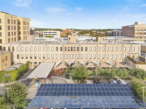 Un immeuble à plusieurs étages, doté d’un toit plat, entouré de verdure et de panneaux solaires.