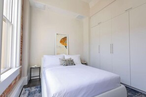 A hotel room with a bed, a nightstand, a window, and a wardrobe. - Stunning 1BR Walkable Loft above Palafox (Pensacola)