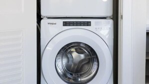 A stacked washer and dryer unit in a laundry room. - The Brent Lofts A Quiet Place 303 (Pensacola)