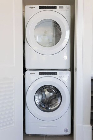 A stacked washer and dryer unit in a laundry room. - The Brent Lofts A Quiet Place 303 (Pensacola)