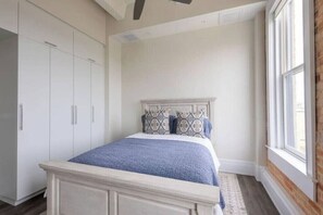 A bedroom with a bed, white wardrobe, and a window. - The Brent Lofts A Quiet Place 303 (Pensacola)