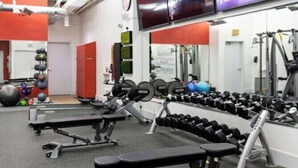 Ett gym med utrustning för styrketräning, träningsbollar och en tv-skärm som visar en reklamfilm.