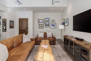 A living room with two sofas, a coffee table, a TV, and framed artwork on the wall. - To Geaux Cups Luxury in The Brent Lofts (Pensacola)