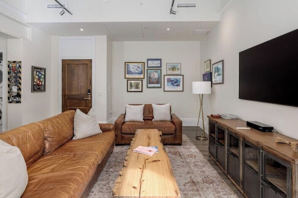 A living room with two sofas, a coffee table, a TV, and framed artwork on the wall.