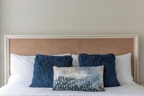 A bed with a white headboard and two blue pillows. - The Brent Lofts Palafox Penthouse (Pensacola)