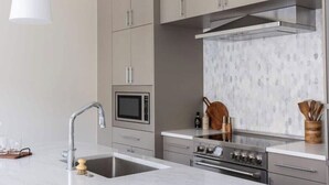 A modern kitchen with a stainless steel sink, a microwave, and a stove. - Cotton, Silk, and Linen at the Brent Lofts (Pensacola)