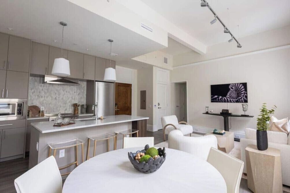 A modern kitchen with a central island, white cabinetry, and stainless steel appliances.