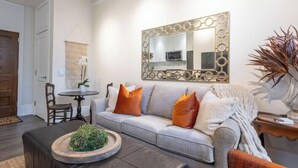 Ein Wohnzimmer mit einer Couch, einem Couchtisch, einem Spiegel und einer Pflanze.