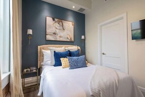 A bedroom with a bed, a wall clock, and a painting. - Chic Hideaway at the Brent Lofts (Pensacola)