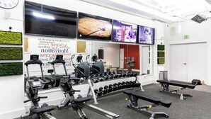 Ein Fitnessraum mit Trainingsgeräten, einer Uhr und motivierenden Plakaten.