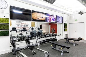A gym with exercise equipment, a clock, and motivational posters. - Chic Hideaway at the Brent Lofts (Pensacola)