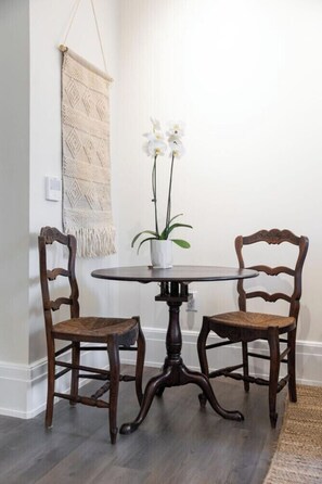 A dining area with a round table and two chairs, a potted plant, and a macrame wall hanging. - Chic Hideaway at the Brent Lofts (Pensacola)