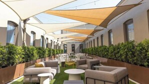 An outdoor seating area with tables and chairs, surrounded by greenery and covered by a canopy. - 2BR Palafox Oasis at the Brent Lofts (Pensacola)