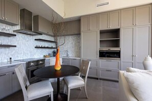 A modern kitchen with grey cabinets, a black dining table, and a vase with branches. - 2BR Palafox Oasis at the Brent Lofts (Pensacola)