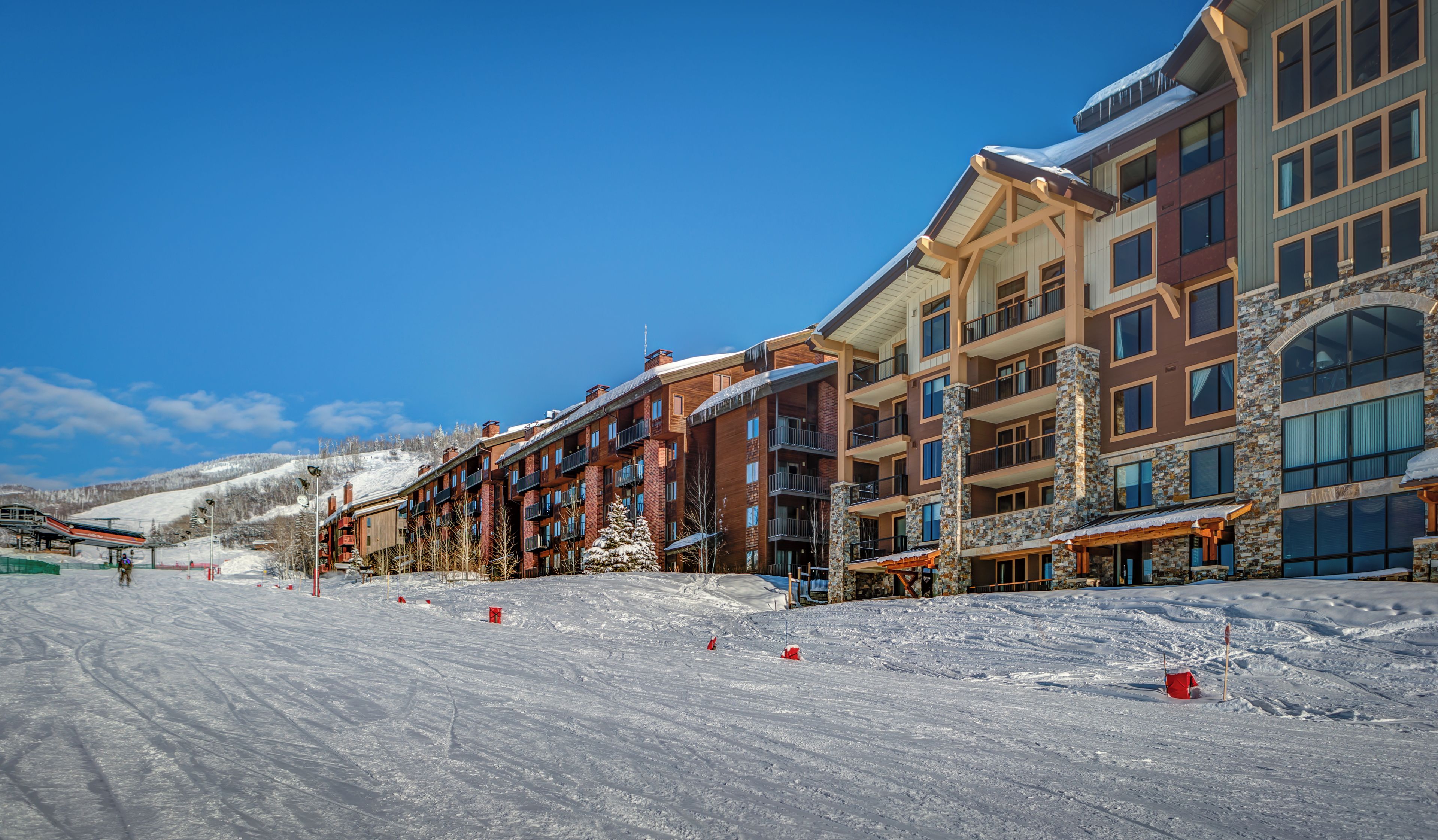 A snow-covered ski slope with multi-story buildings in the background.