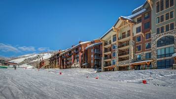 A snow-covered ski slope with multi-story buildings in the background.