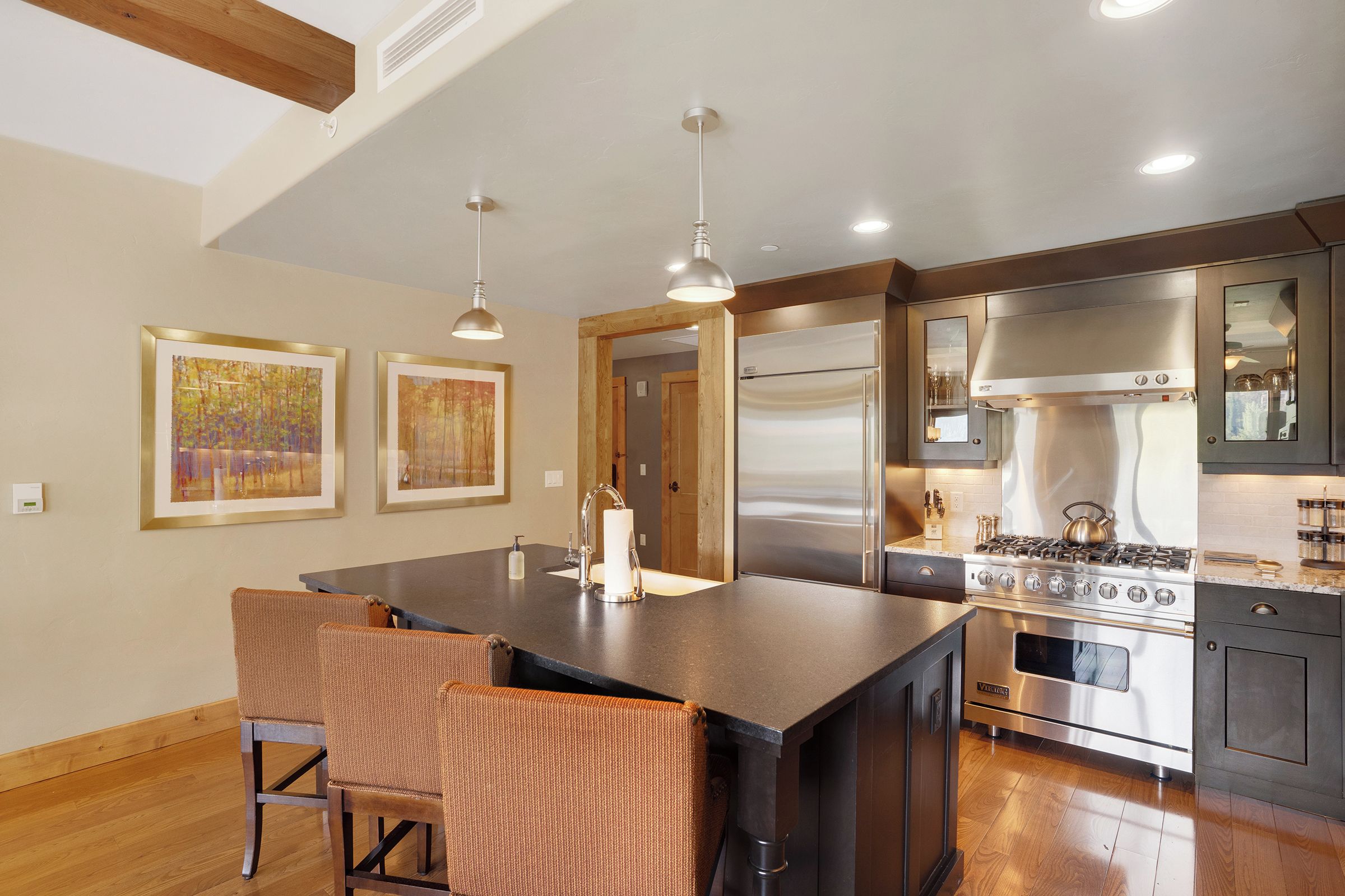 A modern kitchen with a central island, stainless steel appliances, and two pendant lights.