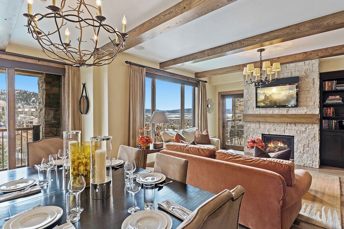 A dining area with a table set for four, a fireplace, and a large window with a view.
